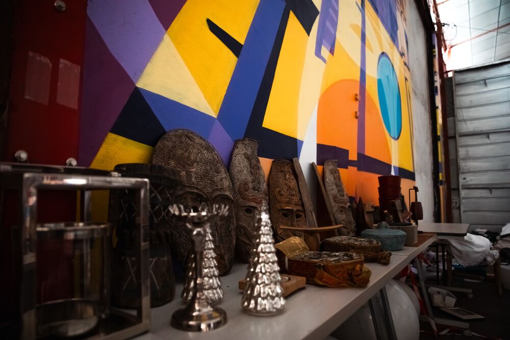 Masques et objets décoratifs devant une fresque colorée